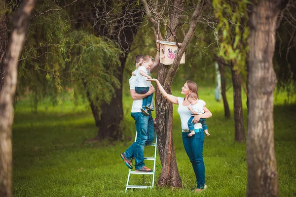 Família feliz com casa de pássaro de madeira — Fotografia de Stock