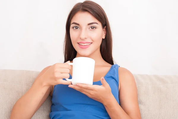젊은 갈색 머리 여자 소파에 앉아서 커피를 마시는 — 스톡 사진