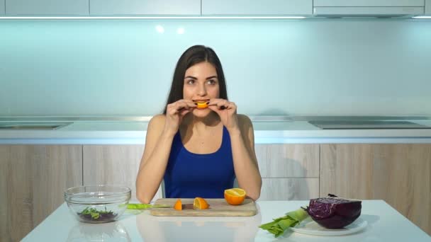 Vrouw die oranje eet in een moderne keuken — Stockvideo