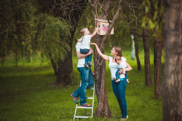 Família feliz com casa de pássaro de madeira — Fotografia de Stock