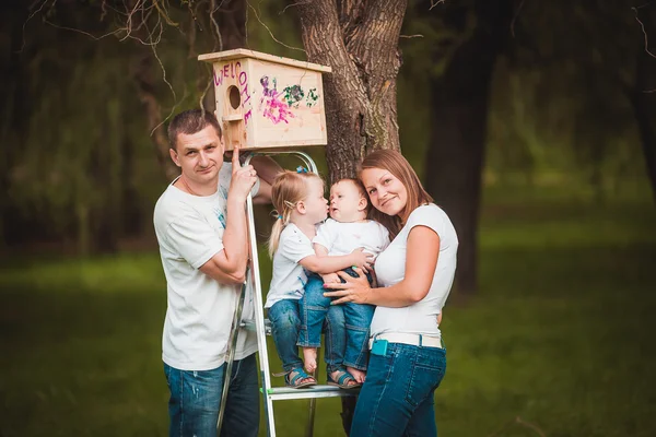 Família feliz com casa de pássaro de madeira — Fotografia de Stock