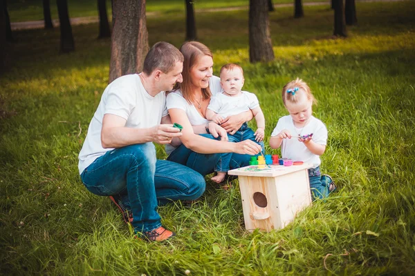 Happy family with nesting box and paints — Stock Photo, Image
