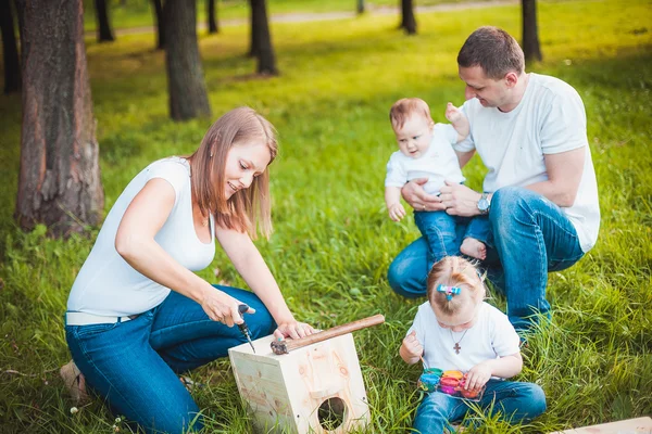 Glückliche Familie mit hölzernem Vogelhaus — Stockfoto