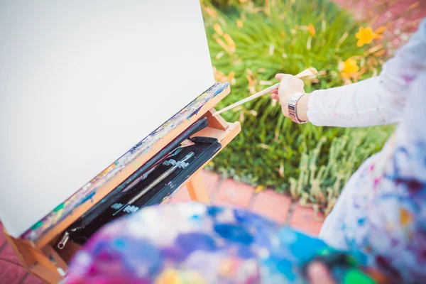 Hand with paintbrush and easel — Stock Photo, Image