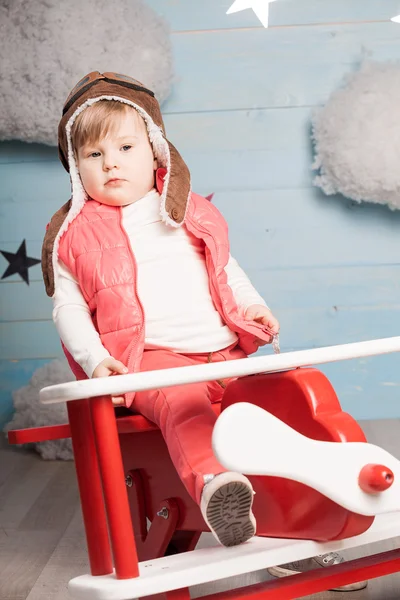 Niña sentada en avión de juguete de madera — Foto de Stock