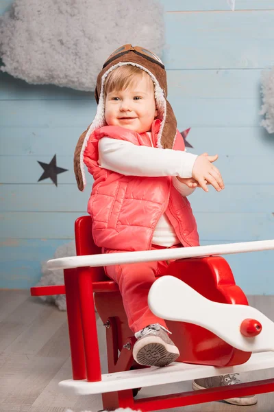 Mała dziewczynka siedzi w płaszczyźnie zabawki drewniane — Zdjęcie stockowe