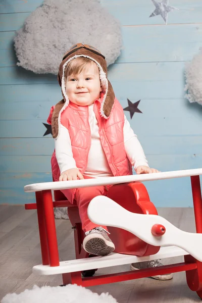 Menina sentada no avião de brinquedo de madeira — Fotografia de Stock