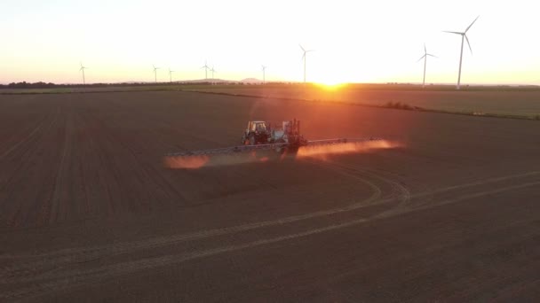 Trator fazendo pulverizador de campo ao pôr do sol — Vídeo de Stock