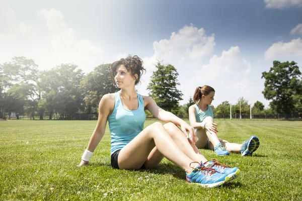 Twee jonge meisjes stetching vóór een joggen — Stockfoto