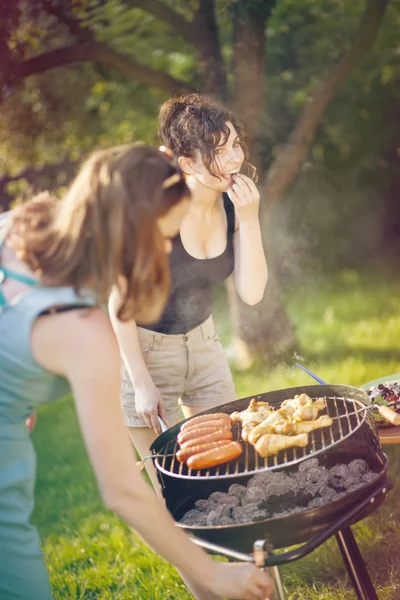 Kaksi nättiä tyttöä tekemässä ruokaa grillillä. — kuvapankkivalokuva