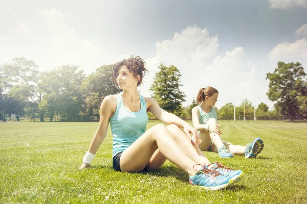 Twee jonge meisjes stetching vóór een joggen — Stockfoto