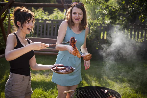 Zwei hübsche Mädchen machen Essen auf dem Grill — Stockfoto