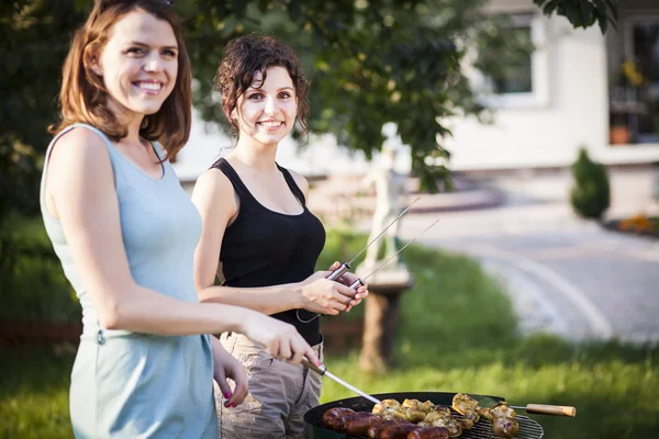 Två vackra flickor att göra mat på grill — Stockfoto