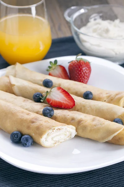 Delicious sweet rolled pancakes on a plate with fresh fruits — Stock Photo, Image