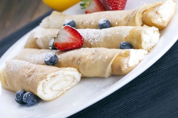 Delicious sweet rolled pancakes on a plate with fresh fruits — Stock Photo, Image