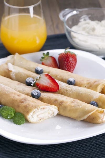 Delicious sweet rolled pancakes on a plate with fresh fruits — Stock Photo, Image