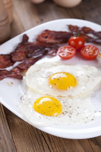 Fried egg and bacon on a plate with spices and vegetables — Stock Photo, Image