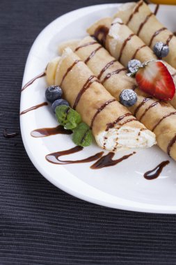 Lezzetli tatlı krep bir tabak taze meyve ile haddelenmiş