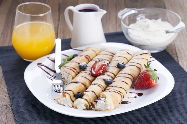 Delicious sweet rolled pancakes on a plate with fresh fruits — Stock Photo, Image