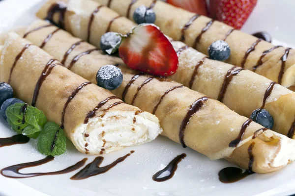 Delicious sweet rolled pancakes on a plate with fresh fruits — Stock Photo, Image