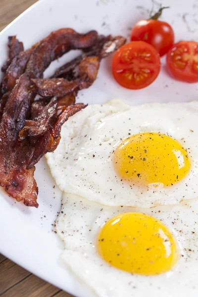 Fried egg and bacon on a plate with spices and vegetables Royalty Free Stock Photos