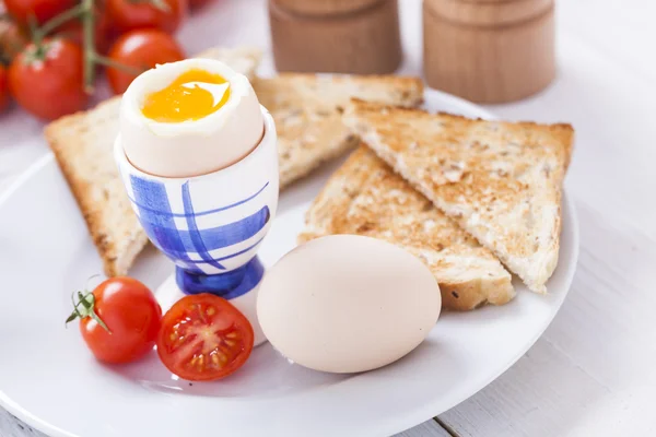 Мягкое варёное яйцо с тостами утром. На заднем плане — стоковое фото