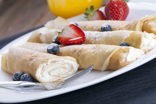 Delicious sweet rolled pancakes on a plate with fresh fruits — Stock Photo, Image