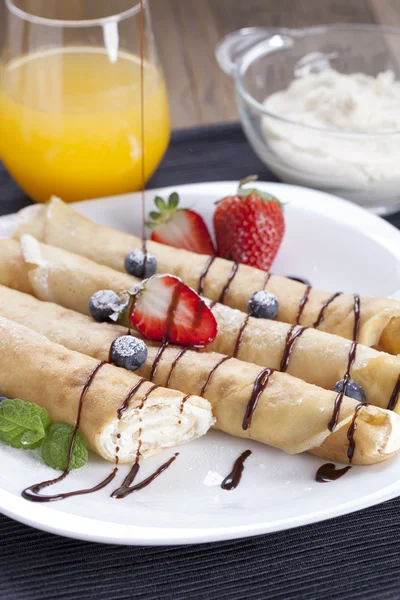 Delicious sweet rolled pancakes on a plate with fresh fruits — Stock Photo, Image