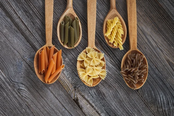 A set of raw pastas on spoons on a wooden table — Stock Photo, Image