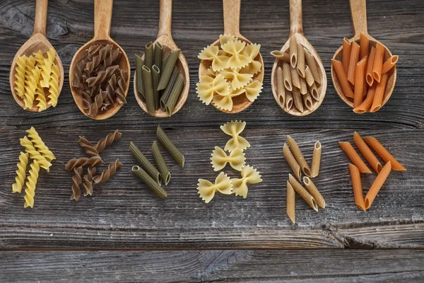 En uppsättning raw pasta på skedar på ett träbord — Stockfoto