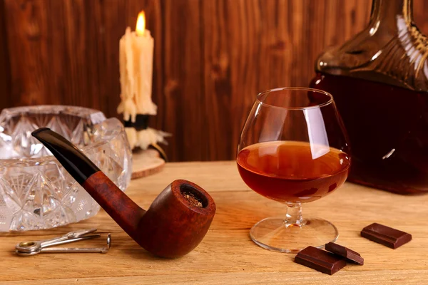 A glass of cognac, chocolate and smoking pipe — Stock Photo, Image