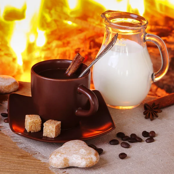 Kaffe med kryddor, mjölk och kakor på bakgrund av en burnin — Stockfoto