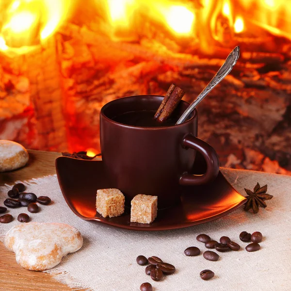 Kaffe med kryddor och kakor på bakgrund av en brinnande eld — Stockfoto
