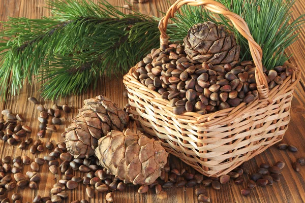 Cedar nuts in a wicker basket on a wooden table — Stock Photo, Image