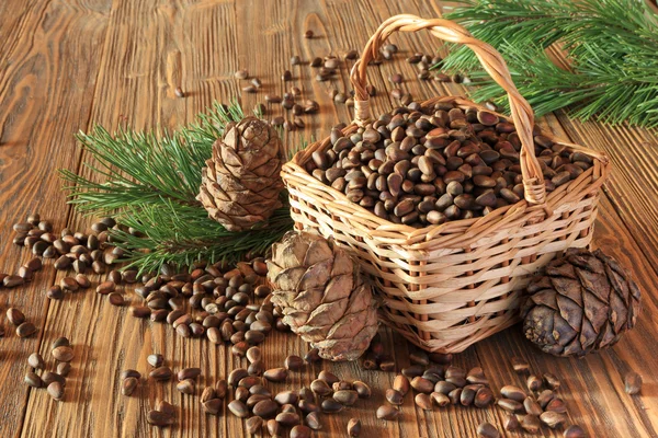 Cedar nuts in a wicker basket on a wooden table — Stock Photo, Image