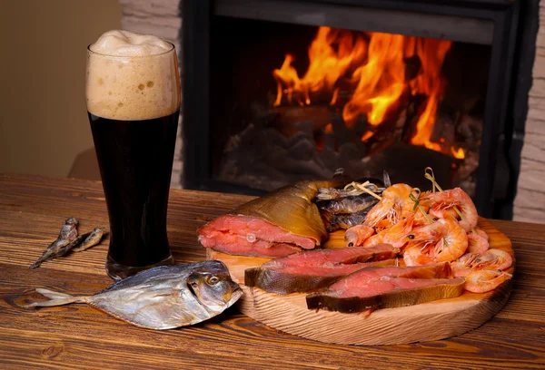 Bicchiere di birra scura e un piatto di pesce sullo sfondo di una buccia — Foto Stock