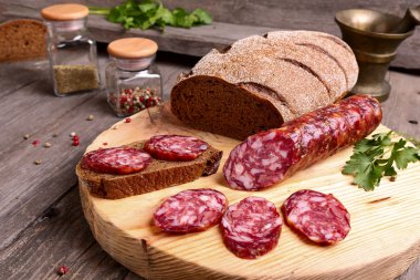 Sliced salami and bread on a cutting board clipart