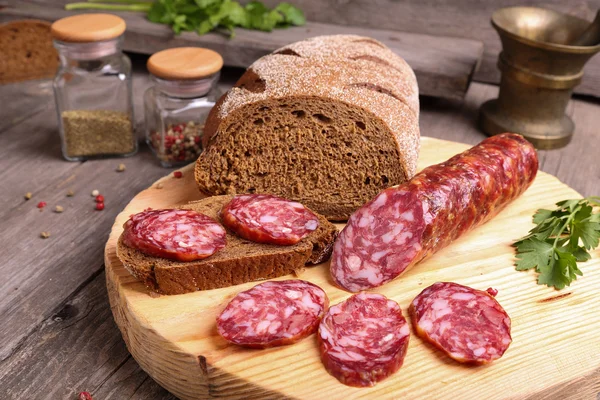 Salami et pain sur une planche à découper — Photo