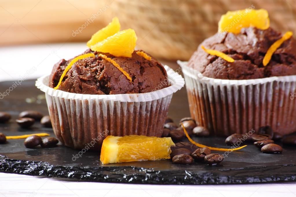 chocolate muffins with oranges on a black tra