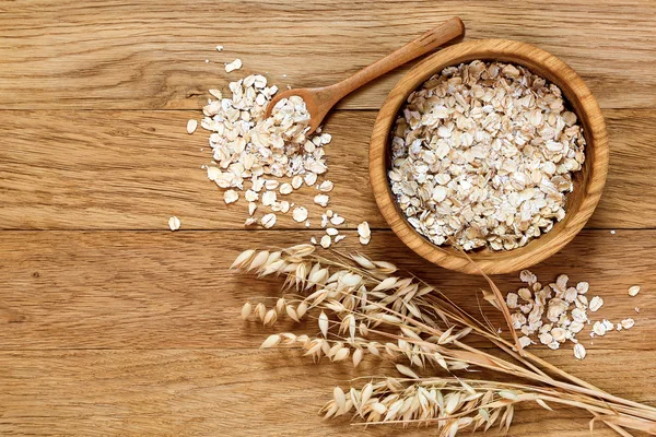 Rolled oats and oat ears of grain on a wooden table — Stock Photo, Image