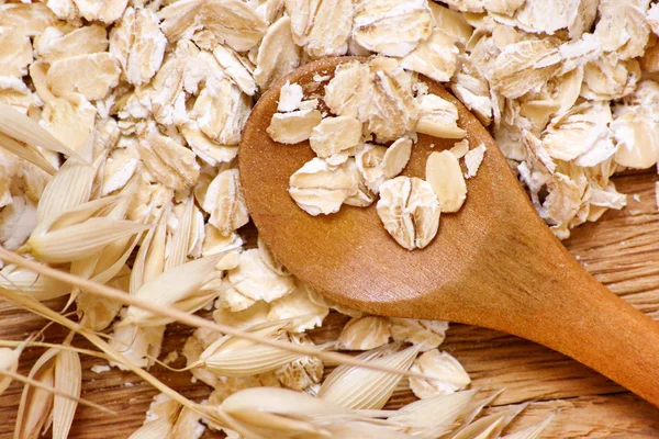 Rolled oats and oat ears of grain on a wooden table