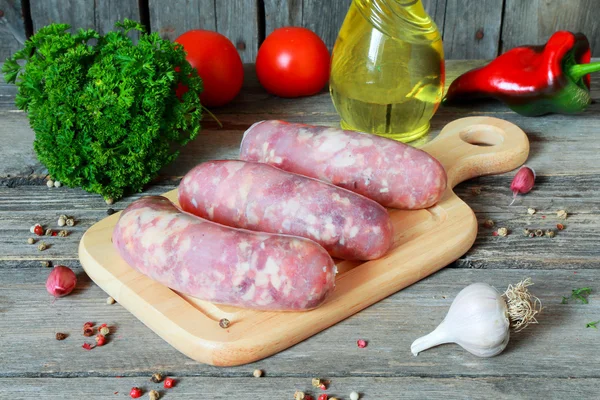 Salsicce di carne cruda su un tagliere — Foto Stock