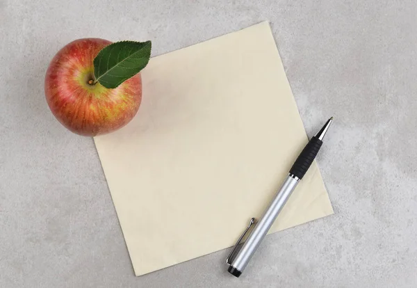 Una Manzana Bolígrafo Una Servilleta Sobre Una Superficie Gris Moteada — Foto de Stock