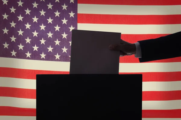 表决概念 用男人的手把选票放在一面美国国旗前的一个盒子里 — 图库照片