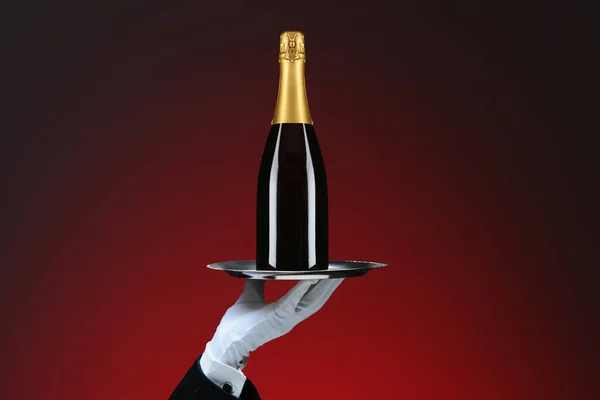 赤い斑点の背景にシャンパンボトルでウェイターの手と銀のトレイの閉鎖 — ストック写真