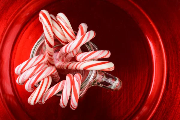 Bastones de caramelo en tarro en la placa roja —  Fotos de Stock