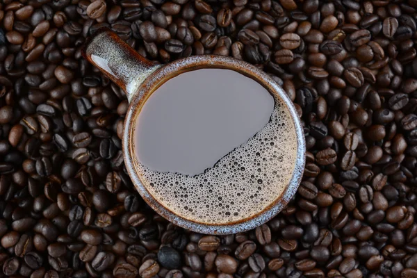 Taza de café rodeada de frijoles asados frescos — Foto de Stock