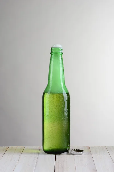 Garrafa única de cerveja com espuma — Fotografia de Stock