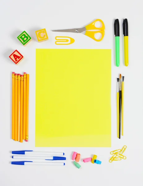 Schoolbenodigdheden rond geel papier — Stockfoto