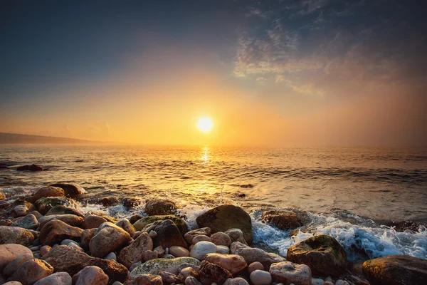 Tropisch farbenfroher Sonnenaufgang am Steinstrand. — Stockfoto